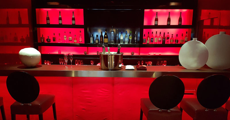 a bar with red lights and bottles