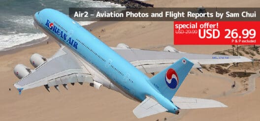 a blue airplane flying over a beach