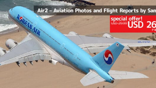 a blue airplane flying over a beach