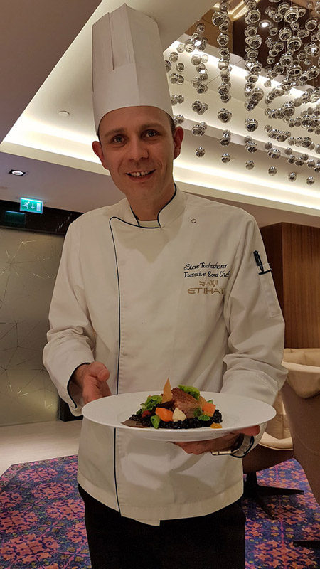 a man in a chef's uniform holding a plate of food