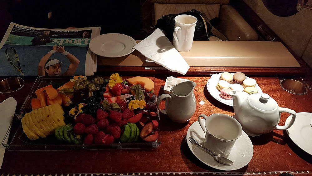 a table with a tray of fruit and a teapot and a magazine