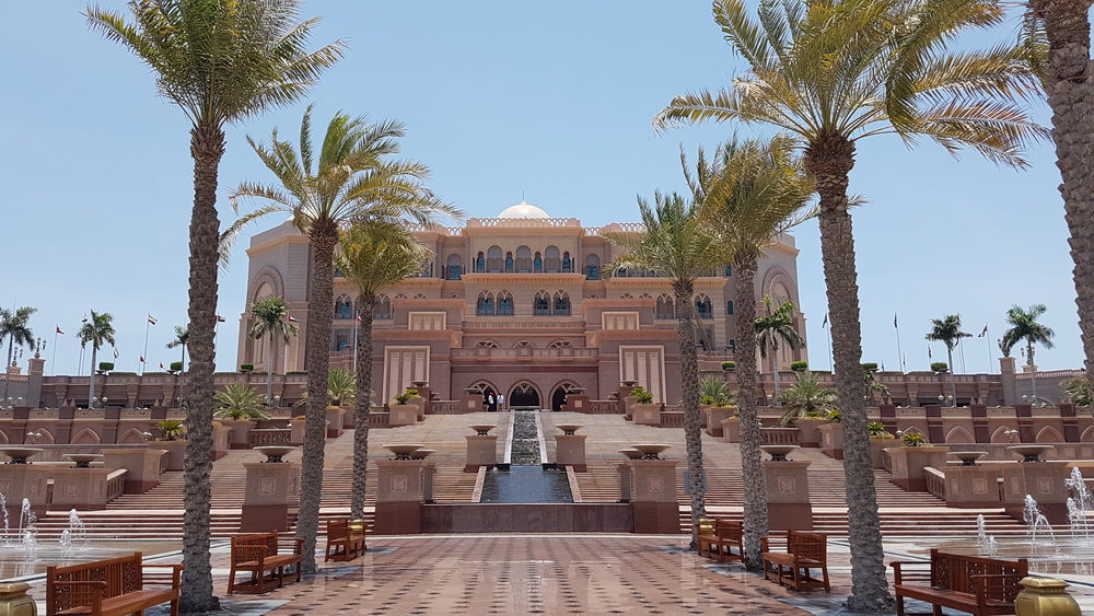 Emirates Palace with palm trees and a fountain