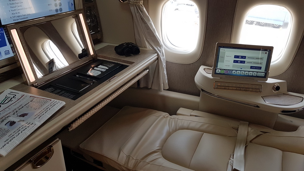 a desk with a mirror and a laptop on the side of a plane