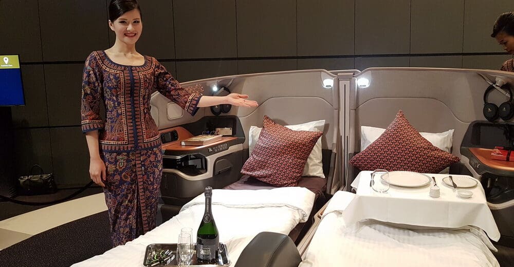 a woman standing in a room with beds and a tray of wine