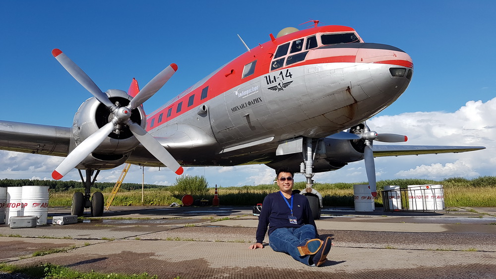 a man sitting on the ground next to a plane