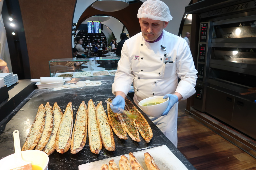 a man in a white coat and white gloves preparing food