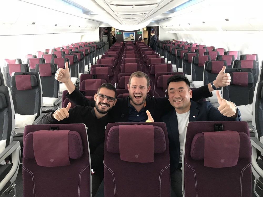 a group of men sitting in an airplane with thumbs up
