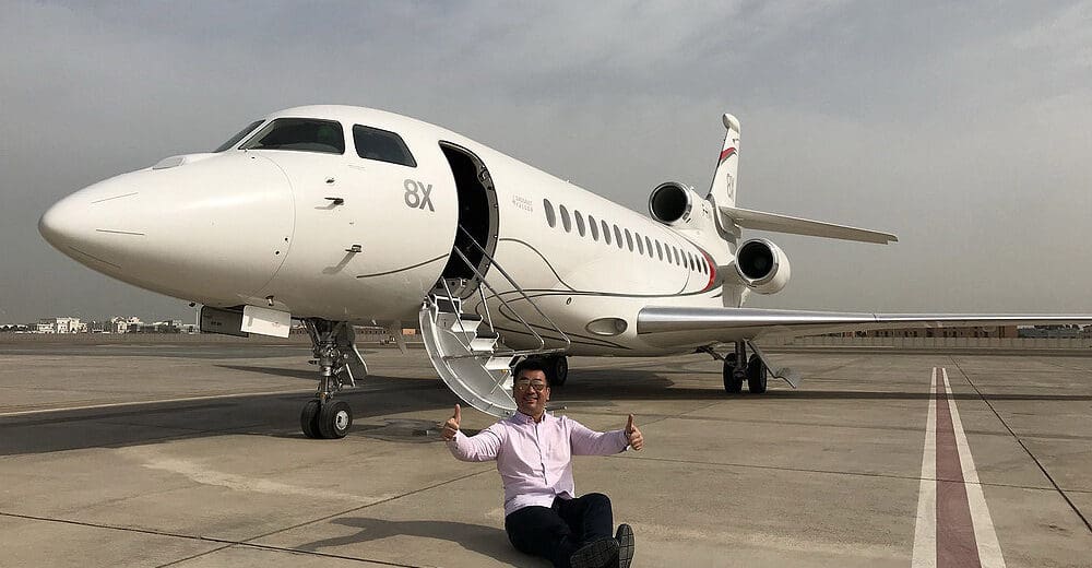 a man sitting on the ground next to an airplane