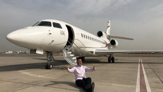 a man sitting on the ground next to an airplane