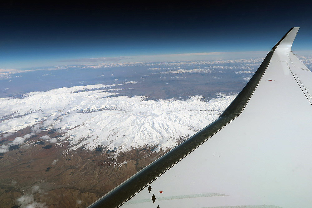 an airplane wing and a snowy mountain