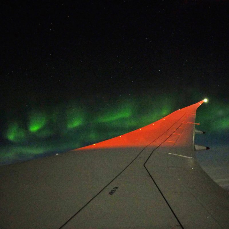 an airplane wing with green lights in the sky