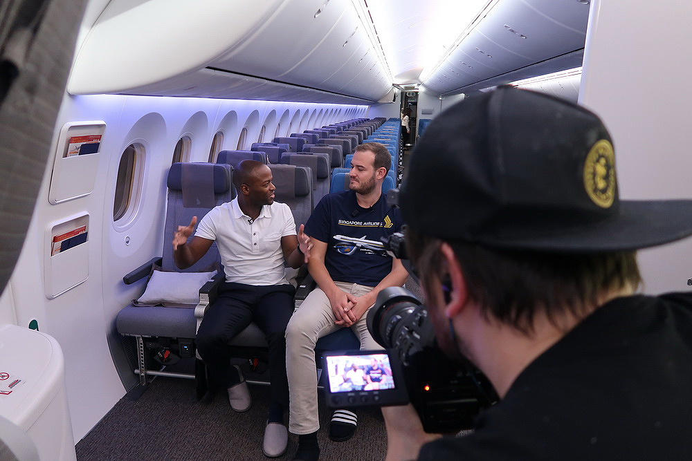 a man taking a picture of two men sitting on a plane