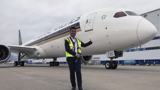 a man in a vest standing in front of an airplane