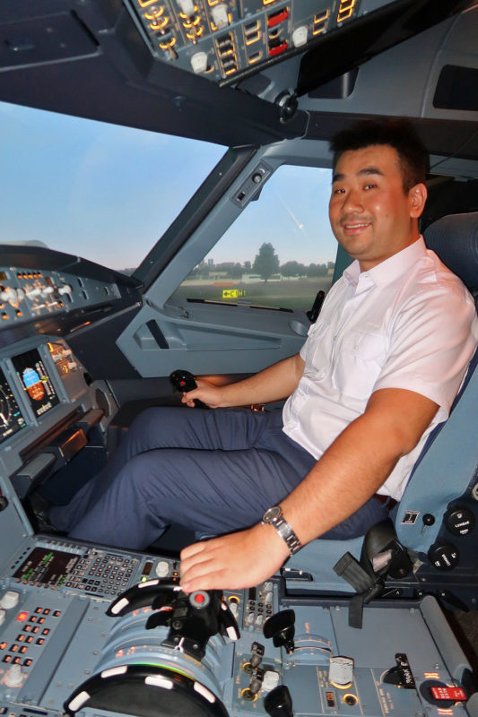 a man in a white shirt and blue pants sitting in a cockpit