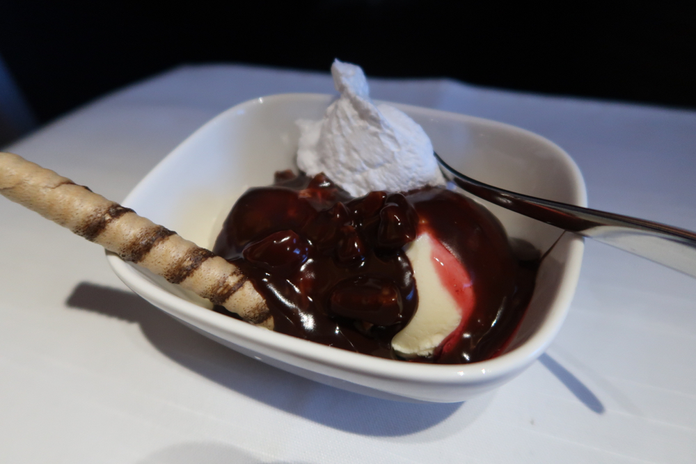 a bowl of ice cream with chocolate sauce and a spoon