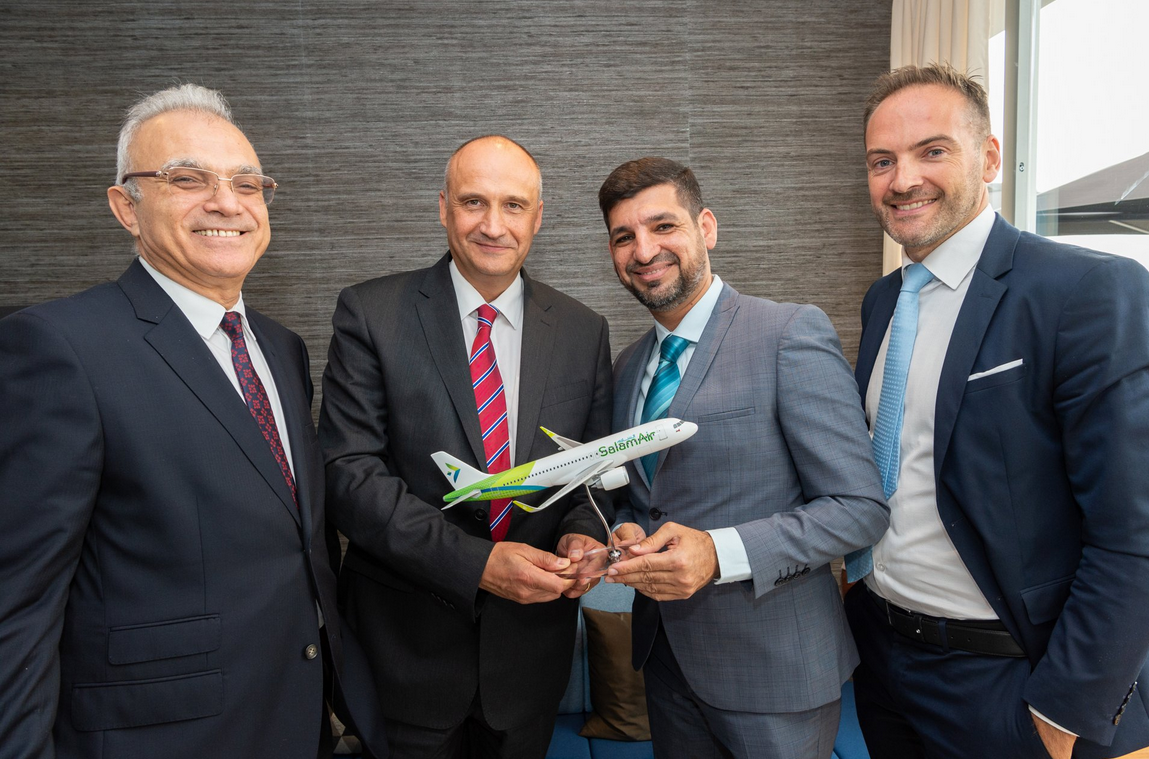 a group of men in suits holding a model airplane