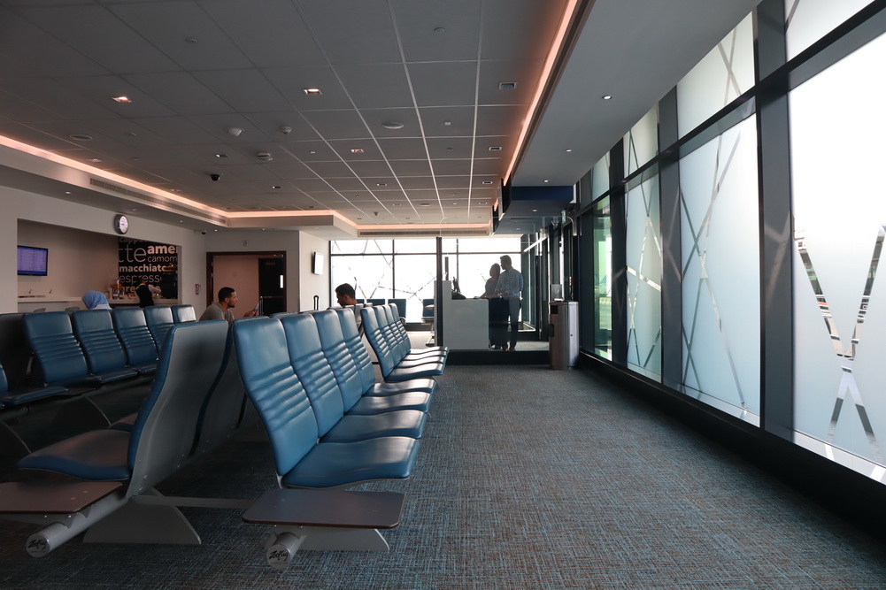 a row of blue chairs in a room with a large screen