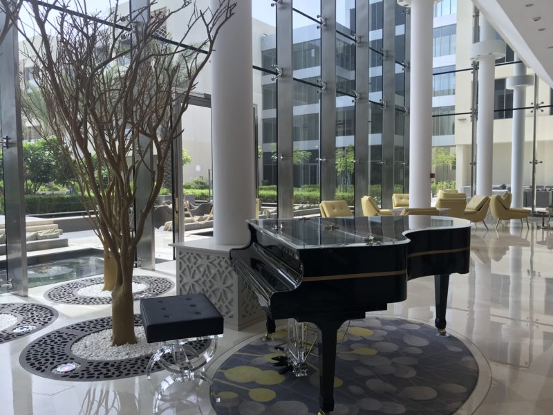 a piano in a room with a tree and a glass wall