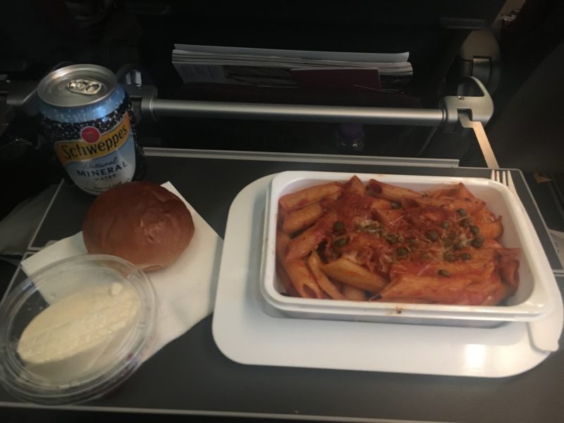 a tray of pasta and a soda can