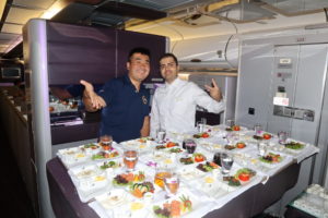 two men standing in front of a table full of food