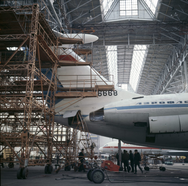 a group of people standing next to a plane in a hangar