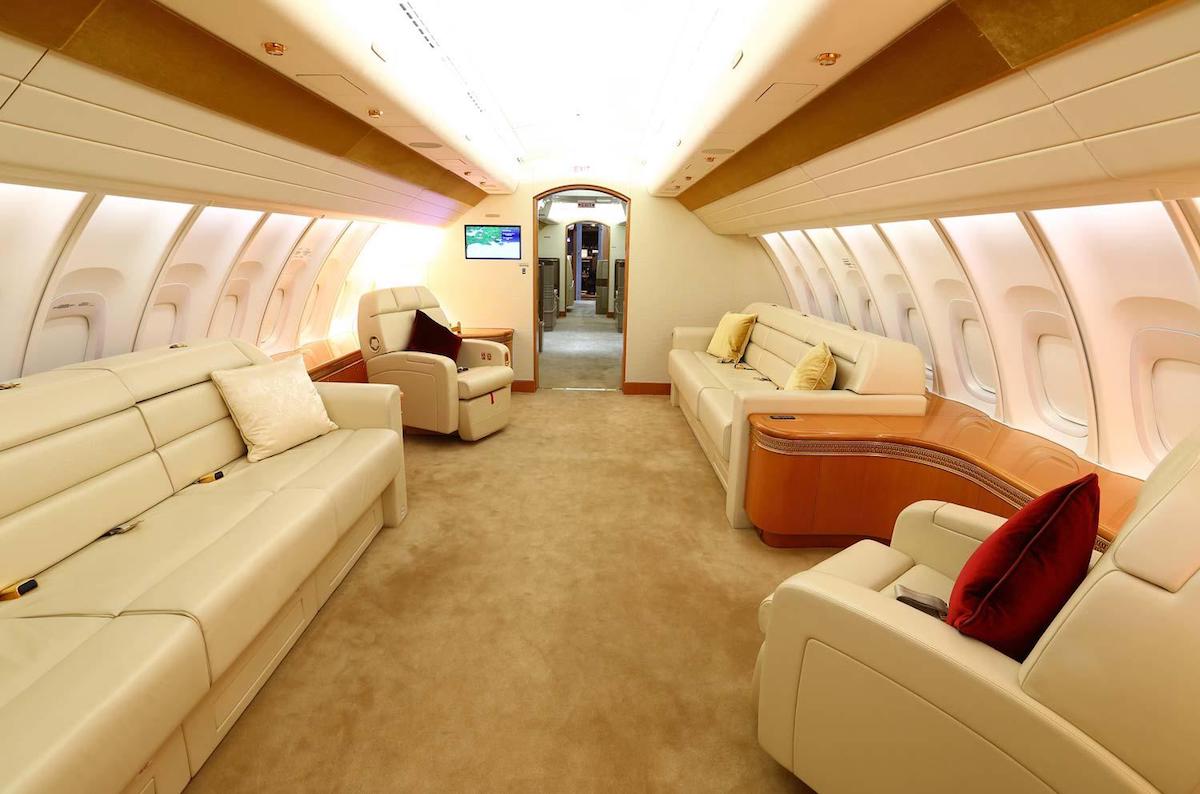 a interior of an airplane with white leather couches and a tan carpet