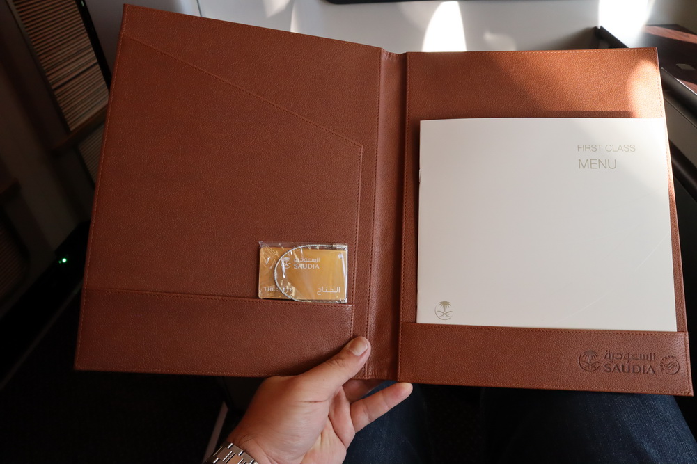 a hand holding a brown folder with a white paper inside