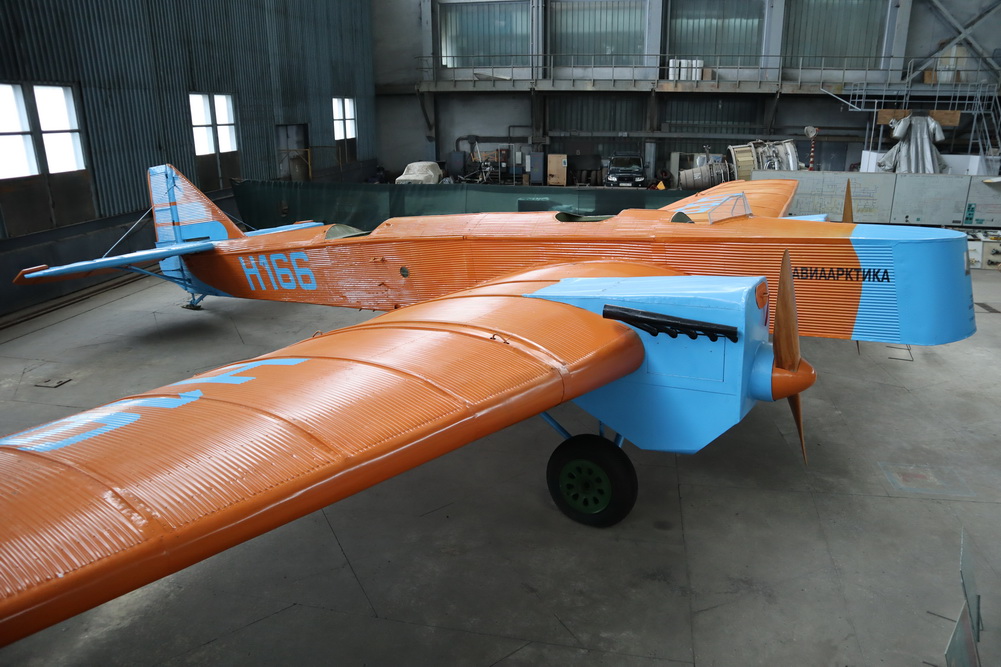 an orange and blue plane in a hangar