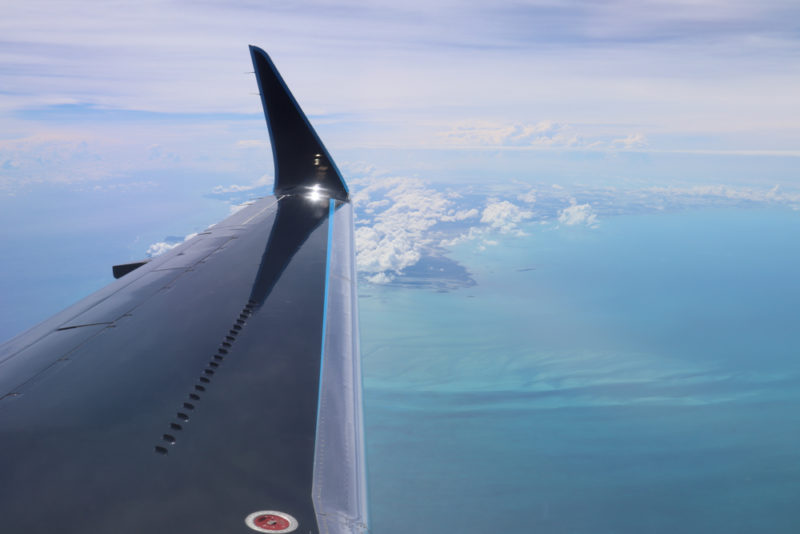 an wing of an airplane above the water