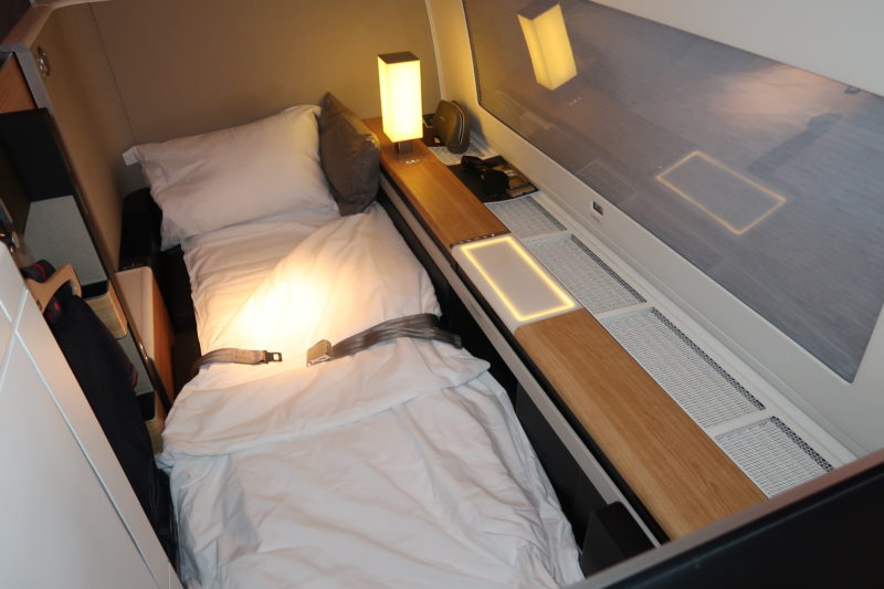 a bed with a seat belt and a lamp on the side