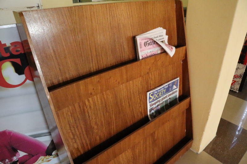 a wooden magazine rack with newspapers in it