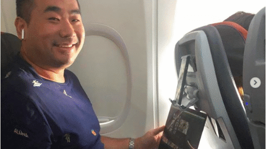 a man sitting in an airplane with a laptop