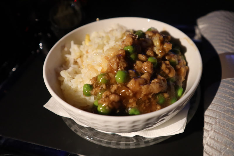 a bowl of rice and meat with peas