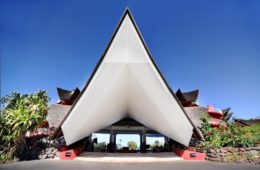 a triangular shaped building with a red wall and blue sky