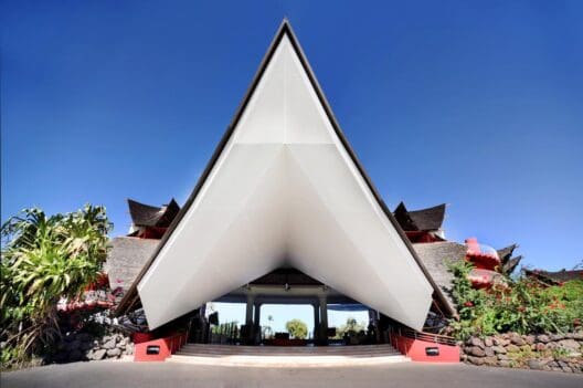 a triangular shaped building with a red wall and blue sky