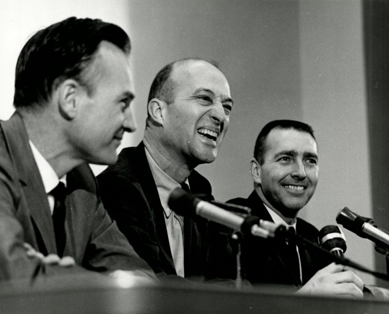 a group of men smiling at a microphone