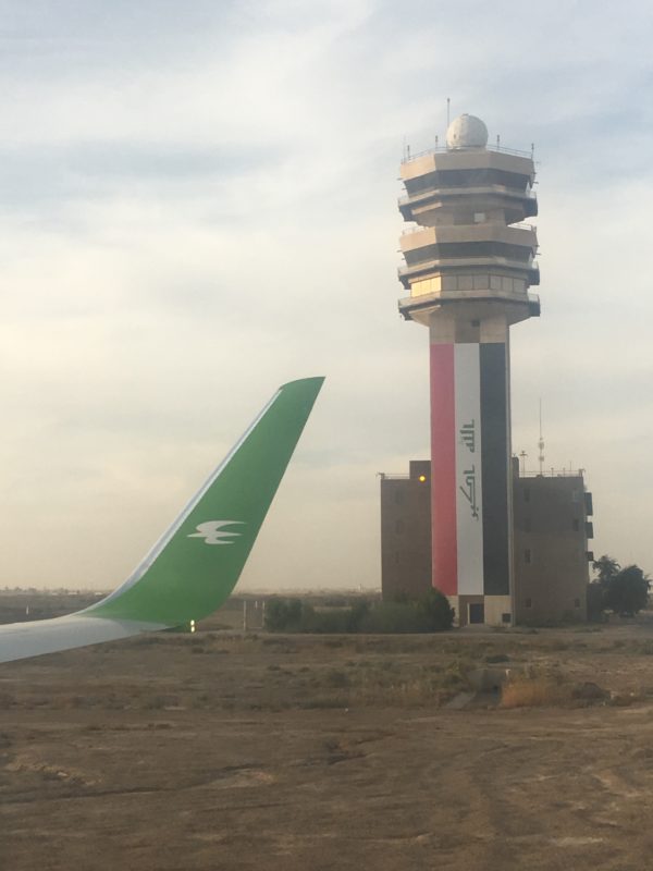 a wing of an airplane near a tower
