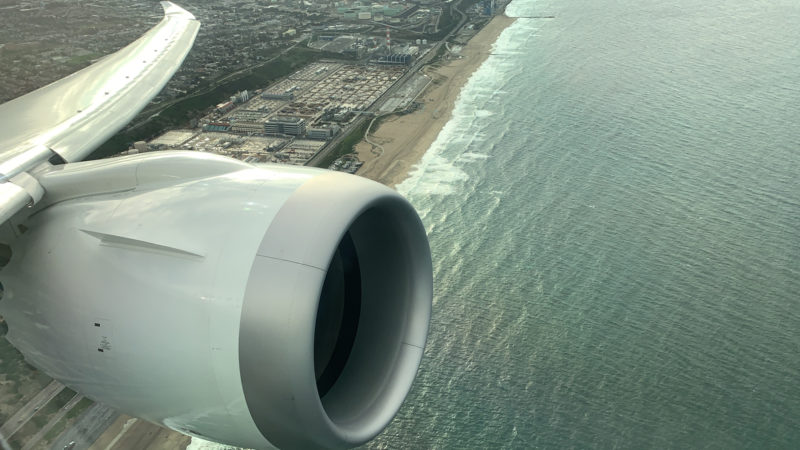an airplane wing with a large engine and a body of water