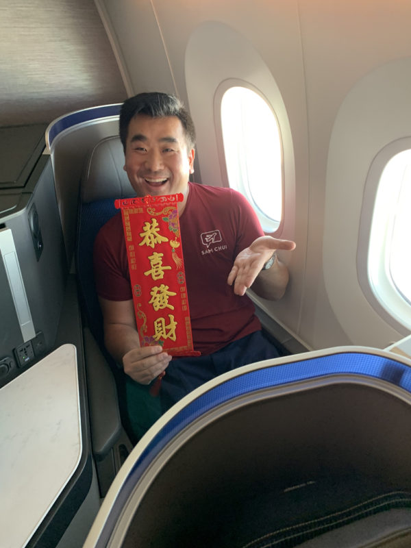 a man sitting in a plane holding a red scroll