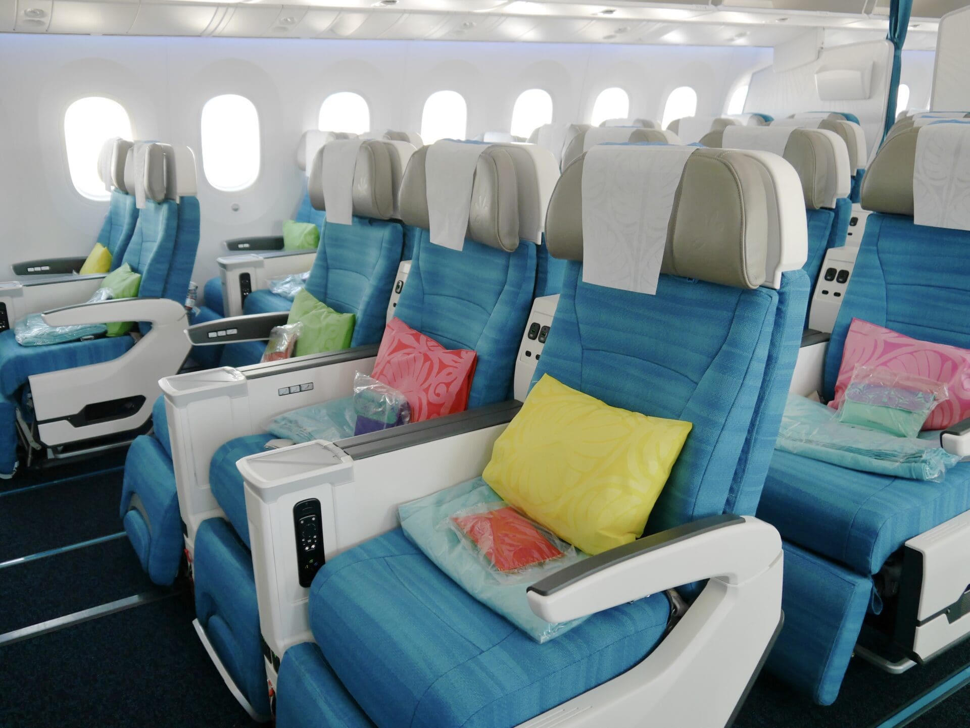 a row of blue chairs with pillows on the side