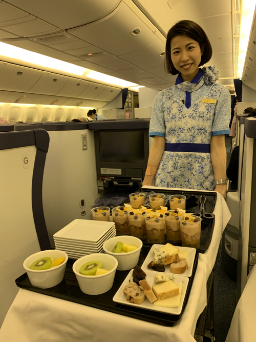 a woman standing in a plane with a tray of food