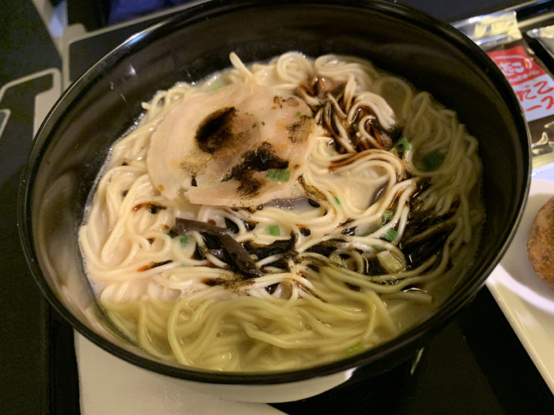 a bowl of noodles with a piece of meat in it