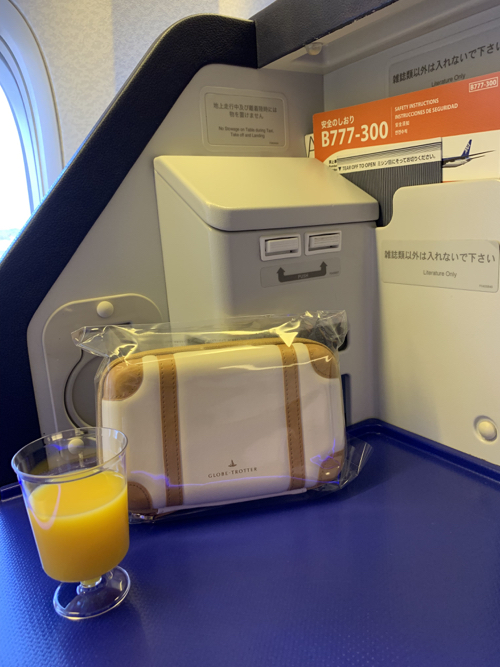 a glass of orange juice next to a bag of luggage