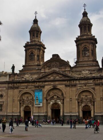 a large building with towers and people walking around