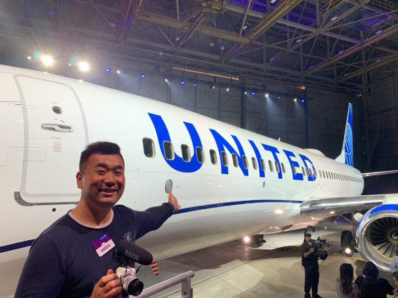 a man holding a camera next to a plane