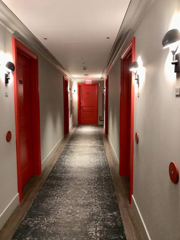 a hallway with red doors and a carpet