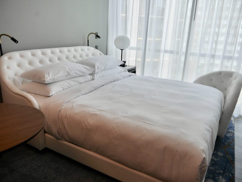 a bed with white sheets and a round table