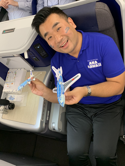 a man sitting on a plane holding two toy planes
