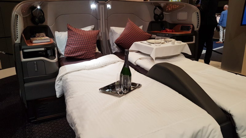 a bed with a tray of wine and glasses on it