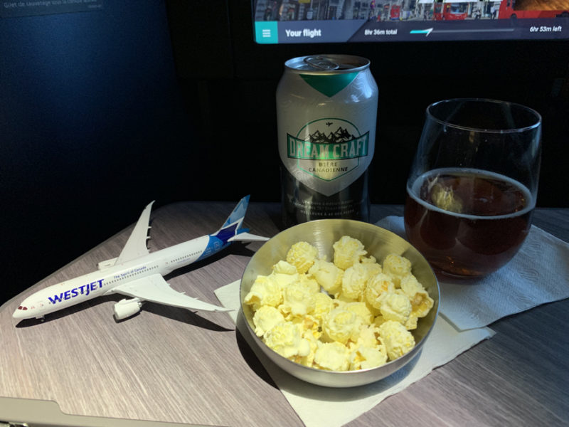 a bowl of popcorn and a beer next to a toy airplane